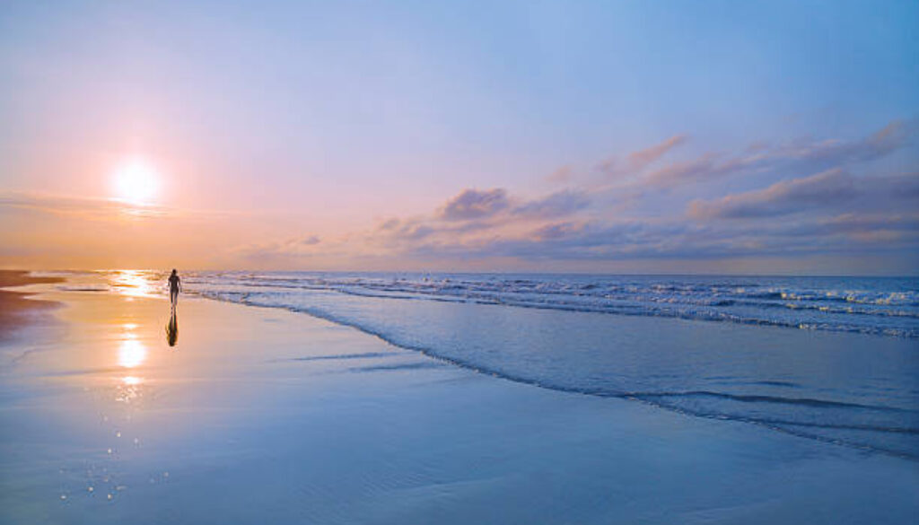 Man walking on beach at sunrise in Hilton Head, South Carolina