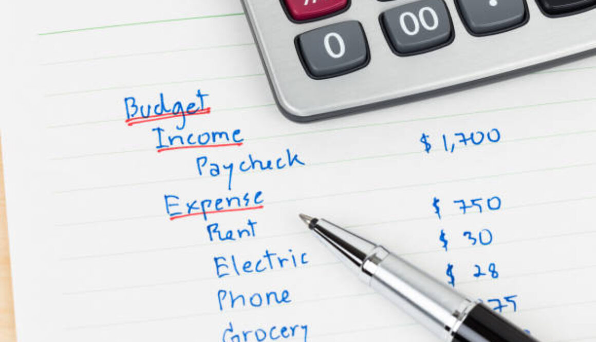 Hand writing home budget with calculator